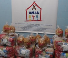 #PraTodosVerem : imagens de cestas básica umas em cima das outras com panetones. Ao fundo há a imagem de um banner com a logo da AMAB.