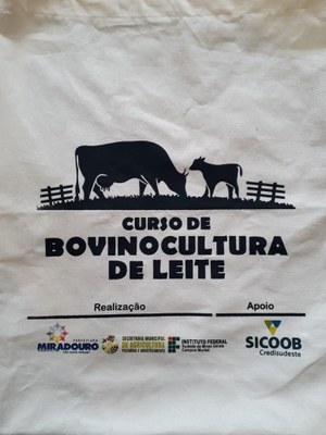 A imagem mostra a estampa da camisa entregue aos participantes do curso de Bovinocultura de Leite. Na peça, o nome do curso é acompanhado da imagem monocromática de dois bovinos, sendo um maior (adulto) e outro menor (filhote), além de duas pequenas cercas. A parte inferior da estampa mostra logomarcas de realizadores e apoiadores.