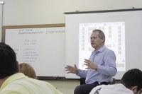 Professor com a imagem da sua apresentação ao fundo.