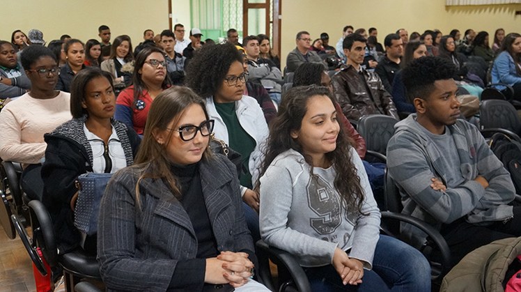 Aula Magna Direito Estudantes do curso de Direito sentados nas cadeiras do Salão Nobre enquanto acompanham a apresentação do professor Gaio.
