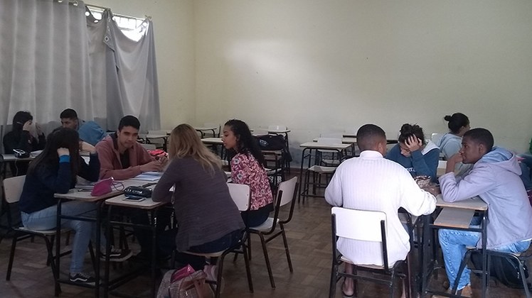 Atividade integração Meio Ambiente #Pratodosverem: Estudantes estão em sala de aula. As carteiras estão organizadas em pequenos grupos. Os jovens discutem o tema dado pelo professor.