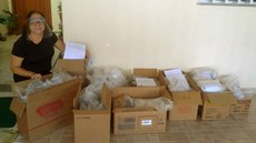 #Pratodosverem: Diretora de Extensão, Elisete Reis, recebe as doações feitas pelo Campus Santos Dumont. Ela está com um dos escudos. Ao lado, as caixas com as demais face shields.