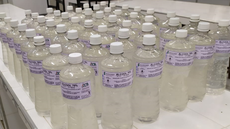 #Pratodosverem: Garrafas de 1 litro de álcool em gel reunidas em uma bancada. Elas são de plástico transparente e estão etiquetadas.