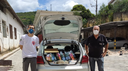 #pratodosverem: Imagem mostra à esquerda professor Carlos Artur Leal (IF Sudeste MG) e à direita representante do Cras Edir Ramos de Faria. Há um carro com porta-malas aberto e com cestas básicas.