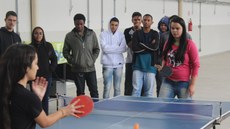 Wanessa e Lisandra jogam tênis de mesa; estudantes assistem à partida