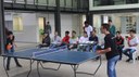 Gabriel Andrade e João Gabriel jogam tênis de mesa; outros estudantes acompanham a partida