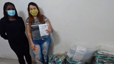 #pratodosverem: Imagem mostra coordenadora da Atenção Básica em Santos Dumont, Paula Guimarães, ao lado da professora Lívia Meneguitte Ávila, do IF Sudeste MG. À direita, estão alguns kits com material para o descarte adequado de resíduo.