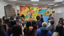#pratodosverem: Imagem mostra estudantes do Partiu IF em frente a mural artístico na Biblioteca Acyr Loureiro Lima, durante guiamento conduzido por alunos do curso técnico em Guia de Turismo