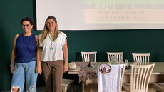 #pratodosverem: Imagem mostra Gicele Brittes e Geísa Soares, em pé, durante palestra em Juiz de Fora sobre projetos desenvolvidos em Conceição do Formoso. Foto cedida por Geísa Soares (arquivo pessoal).