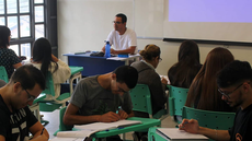 #pratodosverem: Imagem mostra estudantes sentados para trabalho em grupo. Ao fundo, o professor Gabriel Conceição observa e orienta os alunos. Foto de janeiro de 2020, durante oferta de Geometria Analítica e Sistemas Lineares como disciplina de verão.