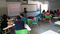 #pratodosverem: Imagem mostra aula da pós-graduação em Práticas Pedagógicas na Educação Contemporânea em 2019. A professora, Iara Nascimento, orienta os alunos, divididos em grupos, sentados em cadeiras dispostas em formato circular.