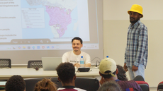 #pratodosverem: Imagem mostra, da direita para a esquerda, o estudante namibiano Erastus Abraham e o professor Lucas Mendes no auditório do Campus Santos Dumont do IF Sudeste MG