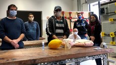 #pratodosverem: Imagem mostra professores e alunos do IF e colaboradora externa do projeto no Laboratório de Instalações e Medidas Elétricas do Campus Santos Dumont. Sobre uma das bancadas, há um reanimador manual.