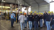 #pratodosverem: Imagem mostra grupo de estudantes, com equipamento de proteção individual, em pé, acompanhando instruções de funcionário da concessionária durante a visita técnica a um dos setores do complexo de oficinas.