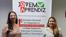 #pratodosverem: Imagem mostra servidoras Marcela Bertolin e Lívia Meneguitte Ávila. Entre elas aparece o banner do  I Encontro Nacional de Integração do Programa Jovem Aprendiz na Rede Federal de Educação Profissional, Científica e Tecnológica.