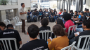 #pratodosverem: Imagem mostra estudantes sentados em cadeiras dispostas em formato de semicírculo no espaço de convivência do Bloco 1 do Campus Santos Dumont do IF Sudeste MG. No centro, professor de Teatro Daniel Meotte está em pé e conversando com os alunos.