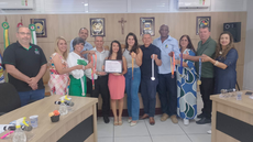#pratodosverem: Imagem mostra vereadores, professores e familiares ao lado de Júlia Mariane, com a placa de moção de congratulação, na Câmara Municipal de Santos Dumont