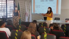 #pratodosverem: Imagem mostra servidoras Maria Cristina Lima e Marcela Bertolin conversando no auditório com novos estudantes do Campus Santos Dumont do IF Sudeste MG. Todos estão utilizando máscara.