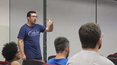 #pratodosverem: A imagem mostra o professor Guilherme, em pé, conversando com grupo de servidores, sentados.
