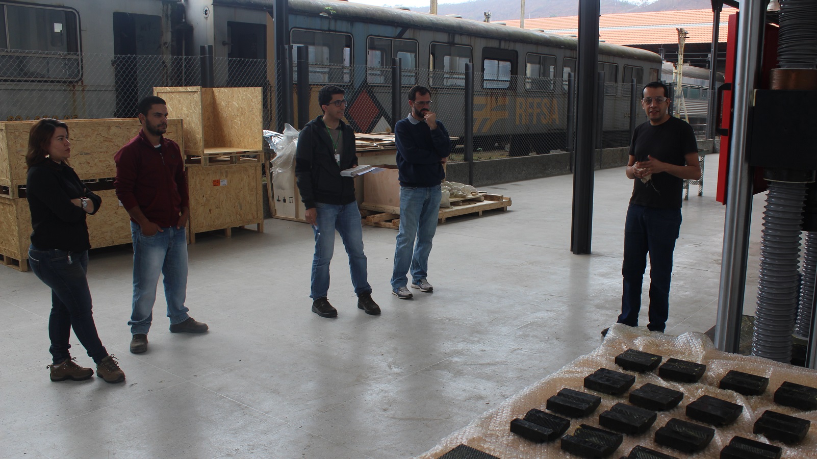 Engenheiro Jurandir Vaz apresenta funcionalidades de máquina universal de ensaios. Quatro servidores do Campus Santos Dumont observam explicação..jpg