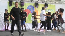 #pratodosverem: Imagem mostra grupo de alunos e servidores do IF Sudeste MG, liderado pelo professor Luciano Gonçalves, durante apresentação no palco do V Simpósio de Ensino, Pesquisa e Extensão (Simepe) do IF Sudeste MG, realizado no Campus Santos Dumont em 2019.