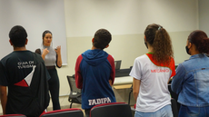 #pratodosverem: Imagem mostra instrutora Amanda Miranda e um grupo de estudantes durante ensaio do Coral do projeto Musicando, no Campus Santos Dumont do IF Sudeste MG.