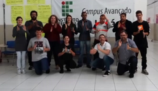 Alunos, servidores e professores, em frente a um banner com a logo do IF, durante atividade em comemoração ao Dia Nacional dos Surdos.